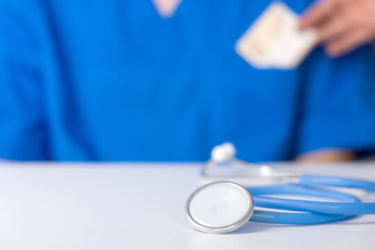 patient giving bribery to doctor. hand putting in pocket some money or putting on the table. corruption problem in medical system, stethoscope close up, medical assistant looking on bancnote.