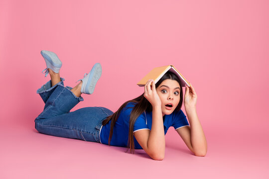 Young Woman With Book on Head Laying on Pink Background