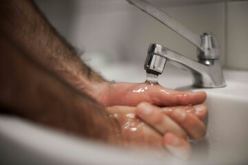 Close up of human hand washing hand on sink.