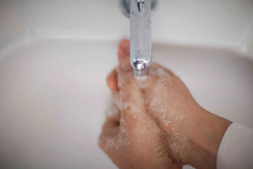Close up of human hand washing hand on sink.