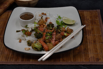 Vegan stir fry and rice on square white plate with chopsticks