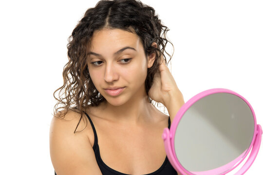 Young woman with curly hair examining herself, self-care and bea