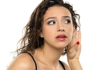 Young woman with makeup, hand near ear, curious expression. Listening intently, gossip concept....