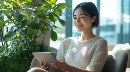 オフィスのラウンジでタブレットを操作する日本人女性のくつろぎ時間