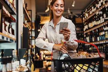 Beautiful young and elegant woman buying some healthy food and drink in modern supermarket or grocery store. Lifestyle and consumerism concept.