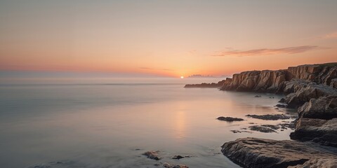 Sunset at rocky coastline with serene water and golden sky during twilight.