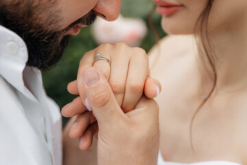 Close-up photo of a man kissing a girl's hand with a wedding ring