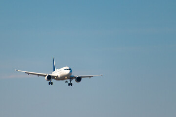 The plane flies in the blue sky for landing