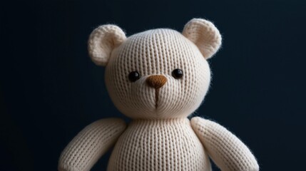 Close-up of a knitted teddy bear. the bear is made of a light-colored yarn and has a round face with two small black eyes and a small nose. © Elena