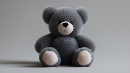 Close-up of a teddy bear sitting on a plain grey background. the bear is made of soft, plush material and has a round face with a black nose and black eyes.