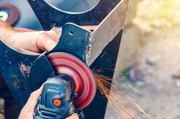 Outdoor metal cutting with angle grinder and sparks for construction project