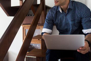 Young casual entrepreneur working on laptop at home office.