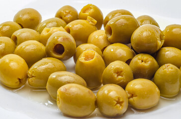 Green olives with pits removed on white surface for a rustic snack