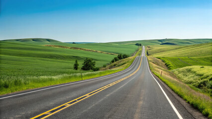 A smooth two-lane highway winding through rolling green fields under a clear blue sky, creating a tranquil, scenic drive with a limitless sense of exploration.