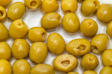 Close-up of green olives with pits removed on white surface for dining