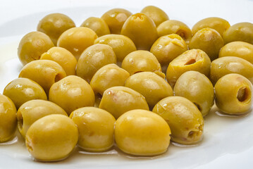 Scattered green olives with pits removed on white surface background