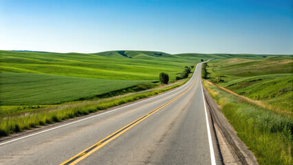 Fototapeta premium A smooth two-lane highway winding through rolling green fields under a clear blue sky, creating a tranquil, scenic drive with a limitless sense of exploration.