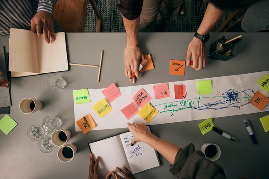 Directly above shot of adhesive notes on conference table with male and female colleagues discussing business plan in of