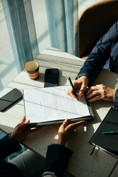 High angle view of female client signing contract with businesswoman in office
