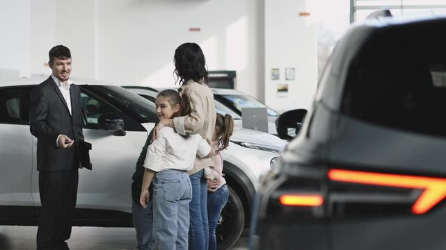 In a modern car dealership, a manager shows and advises a young family with children about buying or test driving a modern car. The concept of buying or leasing a new car.