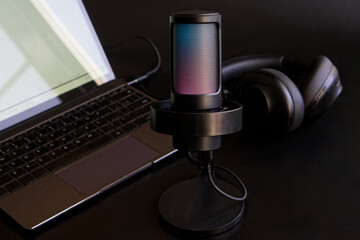 A stylish LED microphone with subtle glow near a laptop and headphones, perfect for streaming, podcasts, music, or ASMR in a sleek, modern setup. Photo