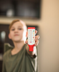 Kid boy teenager monitoring peak expiratory with peak flow meter at home. Hand medical device used to monitor the breath of a person suffering from bronchial asthma.