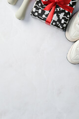 Gym gift box with red ribbon, sneakers, and dumbbells on a marble background. Perfect for fitness...