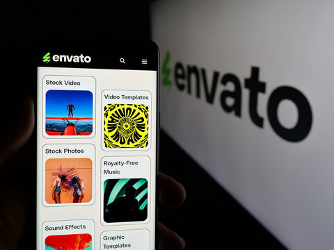 Stuttgart, Germany - 03-07-2025: Person holding web page with logo of Australian content platform company Envato on screen in front of logo. Focus on center of phone display.
