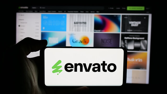 Stuttgart, Germany - 03-07-2025: Person holding cellphone with logo of Australian content platform company Envato on screen in front of business webpage. Focus on phone display.