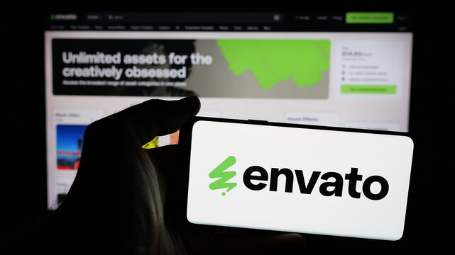 Stuttgart, Germany - 03-07-2025: Person holding mobile phone with logo of Australian content platform company Envato on screen in front of business web page. Focus on phone display.