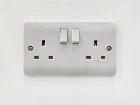Standard British double plug socket with on-off switch. Electrical outlet on a white wall