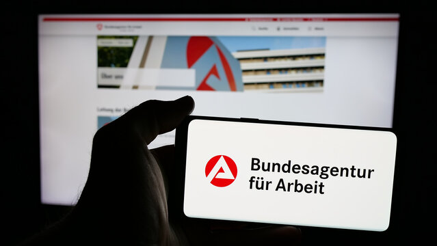 Stuttgart, Germany - 03-07-2025: Person holding mobile phone with logo of German federal agency Bundesagentur fur Arbeit on screen in front of web page. Focus on phone display.