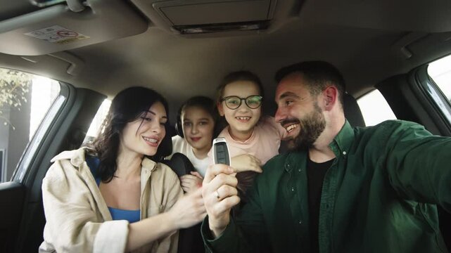 A happy, excited family cuddling up while sitting in a new car and enjoying a purchase at a modern car dealership. Concept of renting, test driving or buying a new car. 