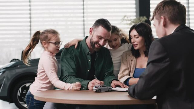A family in the background of a car in a modern car dealership makes a deal to buy a new car with the dealer. The concept of buying or leasing a new car.