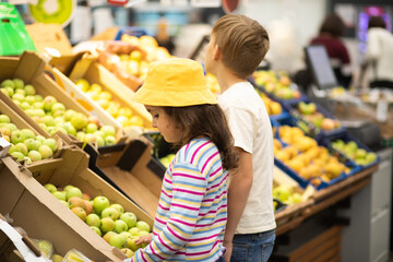 Kids little cute girl and teenager boy shopping for fresh organic fruits and vegetables in supermarket