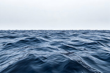 Calm ocean surface with subtle waves under a pale sky