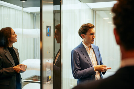 Aff&auml;rsman- och kvinna pratar i hiss i kontorsbyggnad