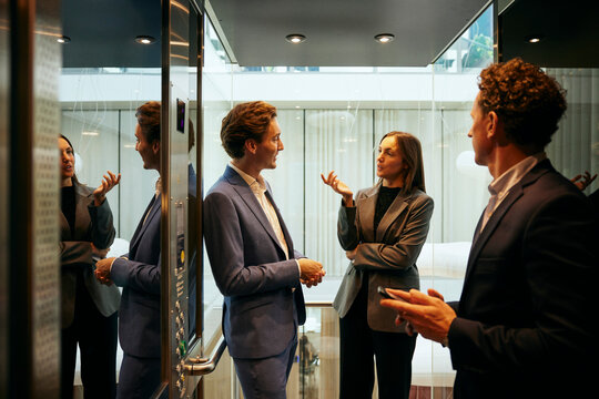 Aff&auml;rskvinna pratar med manliga kollegor i hiss