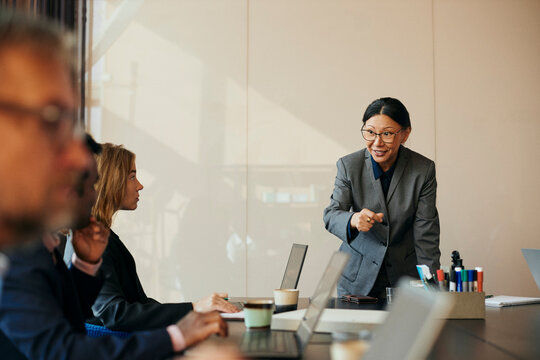 Leende aff&auml;rskvinna pratar med kollegor under m&ouml;te