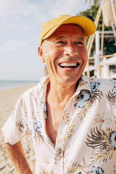 Glad &auml;ldre man med keps p&aring; strand