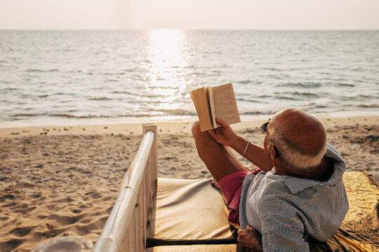 &Auml;ldre man l&auml;ser bok p&aring; strand
