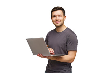 Young man smiling while holding a laptop and standing against a white background in a casual setting