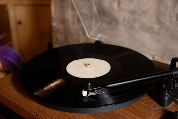 Vintage turntable with vinyl record on a wooden table. After edits.