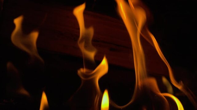 Close up of fire from wood chops in slow motion on black background.