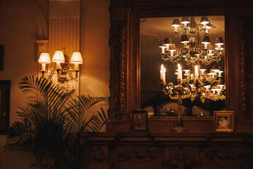 In a dimly lit room, a beautiful chandelier casts its intricate reflections in a mirror, creating...