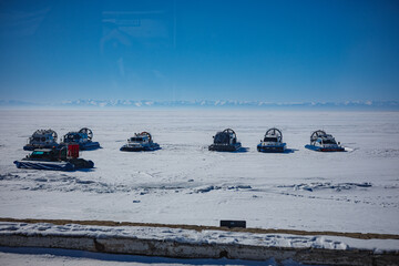 A long row of brightly colored snowmobiles is parked meticulously in the untouched snow, ready for...