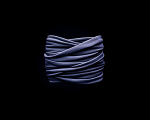 Dark purple fabric tightly wrapped in a square shape against a black background