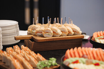 A buffet table that is beautifully arranged with a variety of sandwiches and fresh fruit placed elegantly on it for guests to enjoy