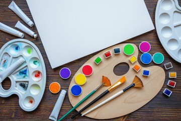 Palettes, paper for watercolor painting, watercolor paints, tubes and paintbrushes. Copy space