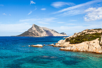 Turquoise waters meet rocky shores in Sardinia, Italy. The island's coastline offers a stunning...